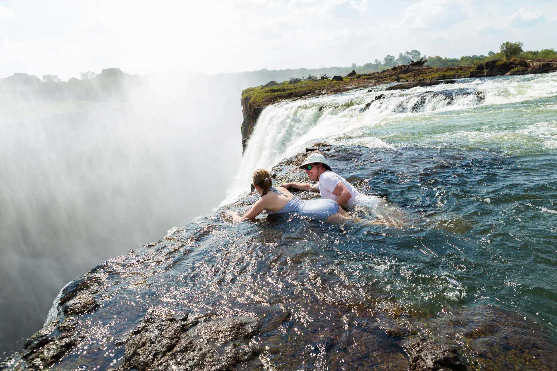 Man and young girl standing in the water at Devil’s Pool, Victoria Falls, Zimbabwe/Zambia